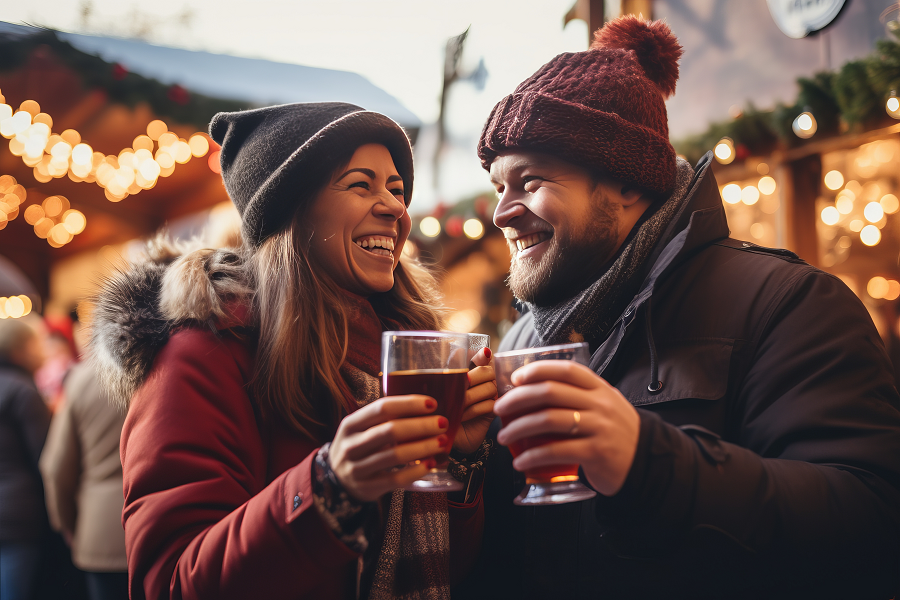 A young couple enjoy a Christmas market with mulled wine on a winter holiday.